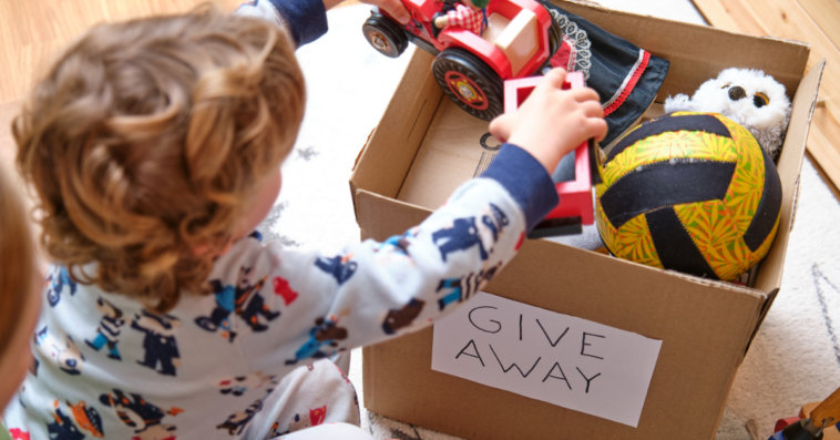 child puts toys in box to be donated