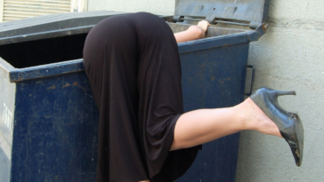 woman searching in dumpster