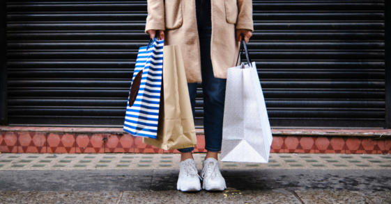 person on sidewalk holding shopping bags