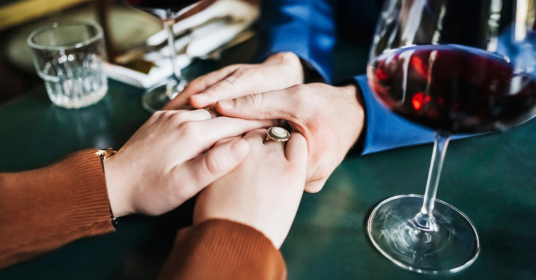 couple holds hands on table