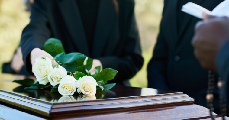 young woman places roses on a casket at funeral