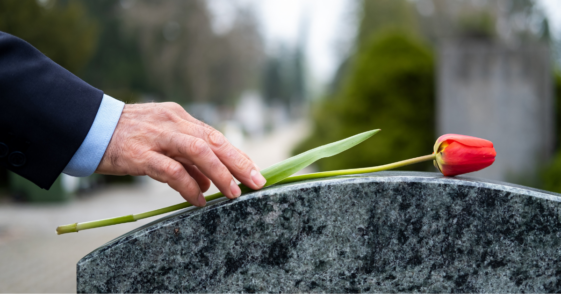 Man placing flower on tombstone