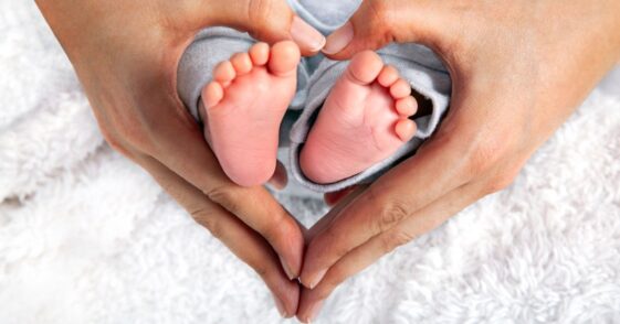 Baby's Feet In Heart Shaped Hands