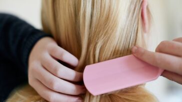 Rearview shot of a young blonde woman brushing hair.