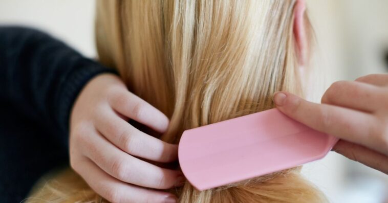 Rearview shot of a young blonde woman brushing hair.