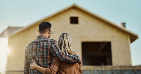 A young couple looking on the foundation of a house.