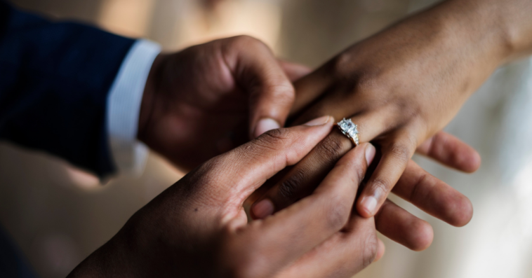 A man putting a ring on a woman's finger.