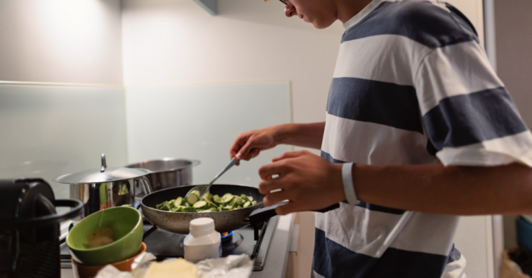 A teenage boy cooking on a stovetop