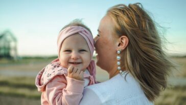 Mother standing while holding happy baby girl