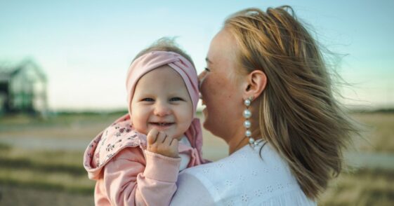 Mother standing while holding happy baby girl