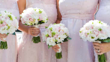 A line of bridesmaids wearing pink dresses and holding bouquets.