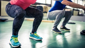 Two people doing squats at gym