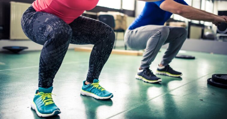 Two people doing squats at gym