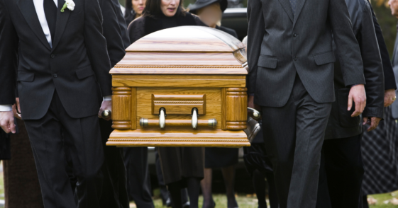 people carrying casket to grave at cemetery