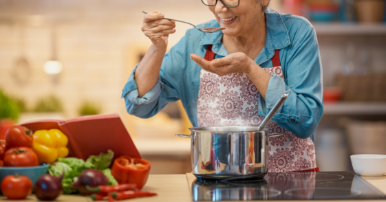 older woman tasting sauce cooking in dutch oven