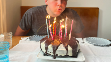 Teen boy blowing out birthday cake candles