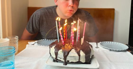 Teen boy blowing out birthday cake candles