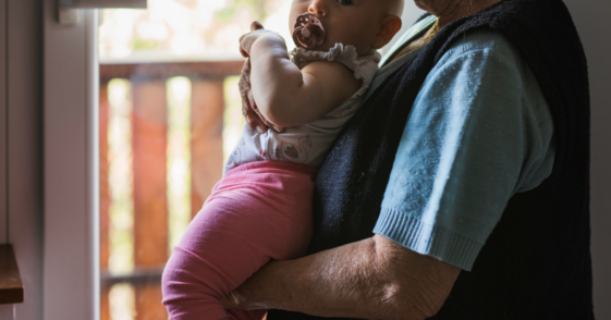 An elderly woman holding a baby in her arms.