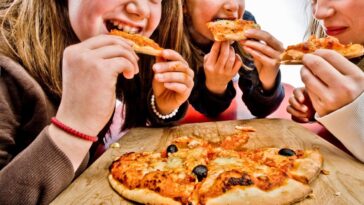 Three teenage girls eating pizza.