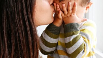 Young mother kissing baby son's forehead