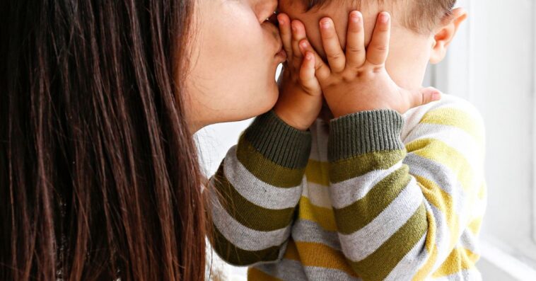 Young mother kissing baby son's forehead