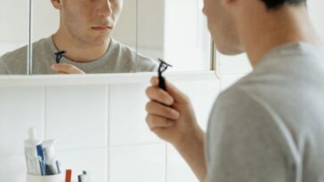 Teenager facing mirror while holding razor blade