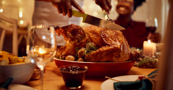 person carving turkey at dinner table