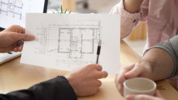 couple looking at house blueprints with architect