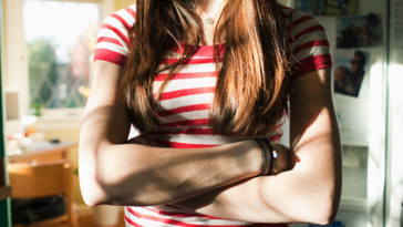 A teenage girl crossing her arms.