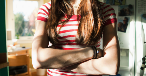 A teenage girl crossing her arms.