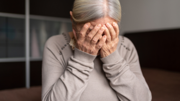 An older woman crying into her hands.