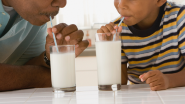 A man and a boy both drinking milk from a straw.