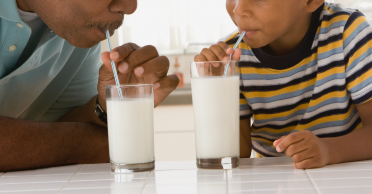 A man and a boy both drinking milk from a straw.