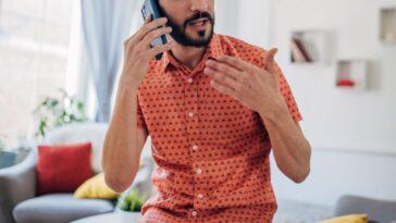 One man, talking on mobile phone in living room at home.