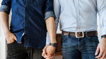 Close up shot of a gay male couple holding hands. Focus on their hands.