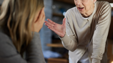 An older woman gesturing to a younger woman with her head in her hands.