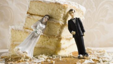 Wedding cake visual metaphor with figurine cake toppers. The toppers of a bride and groom are leaning against a crumbled piece of vanilla wedding cake.