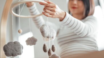 Pregnant mother putting up mobile in nursery