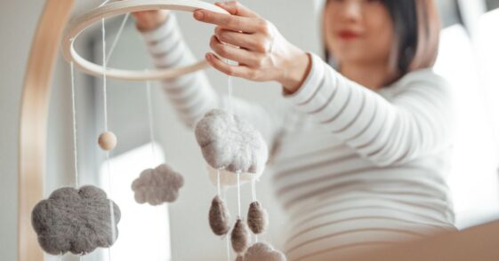 Pregnant mother putting up mobile in nursery