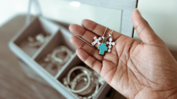 person holding pendants over an open jewelry box