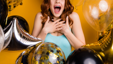 woman surrounded by balloons acting surprised