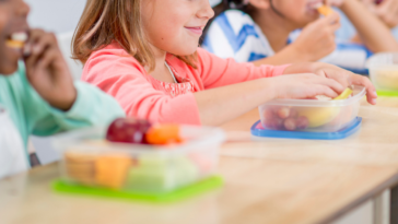 four kids eating lunch at their desk in school