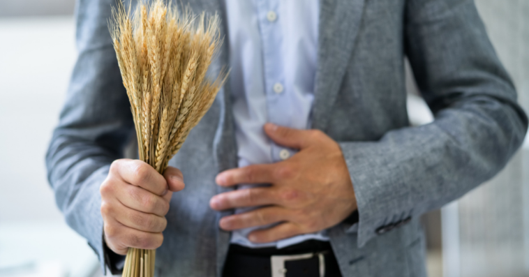 A man holding a pile of wheat with his other hand on his stomach.