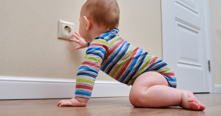 A baby crawling up to an outlet.