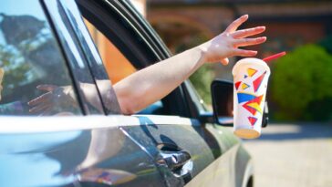 Person discarding a soft drink cup out car window