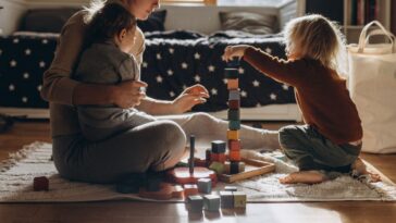 Woman playing toy blocks with two children