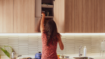 A woman organizing a kitchen cabinet.