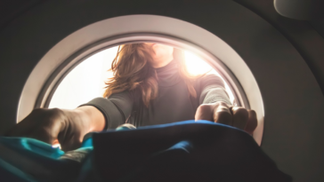 woman reaching into front load dryer to get laundry