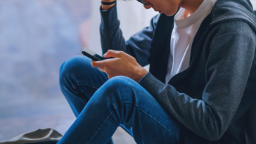 upset teen boy looking at a cellphone