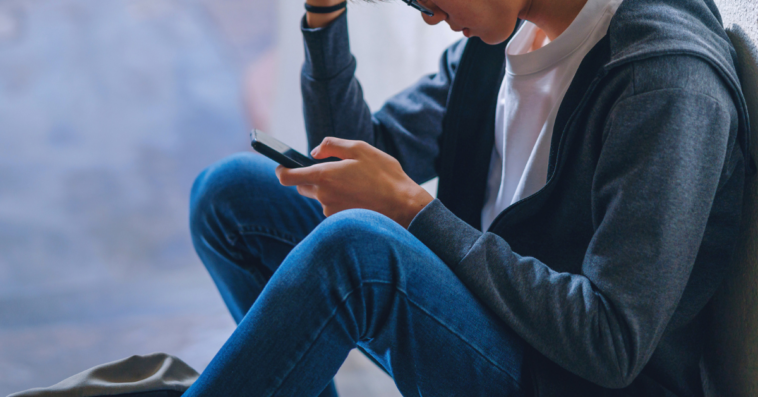 upset teen boy looking at a cellphone